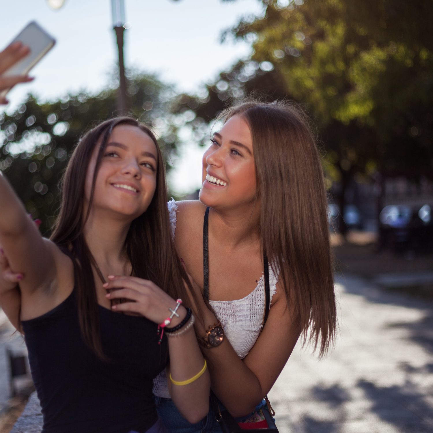 Two women smiling at their phone whilst taking a selfie